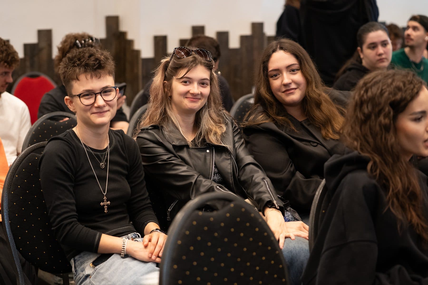 Trei studente zâmbitoare în public, la o întâlnire Liderii de Mâine