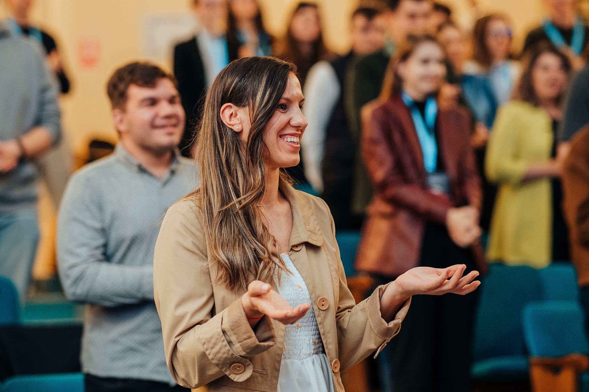 Participantă care râde și gesticulează cu palmele deschise în mijlocul mulțimii, la conferința Ready for the Future