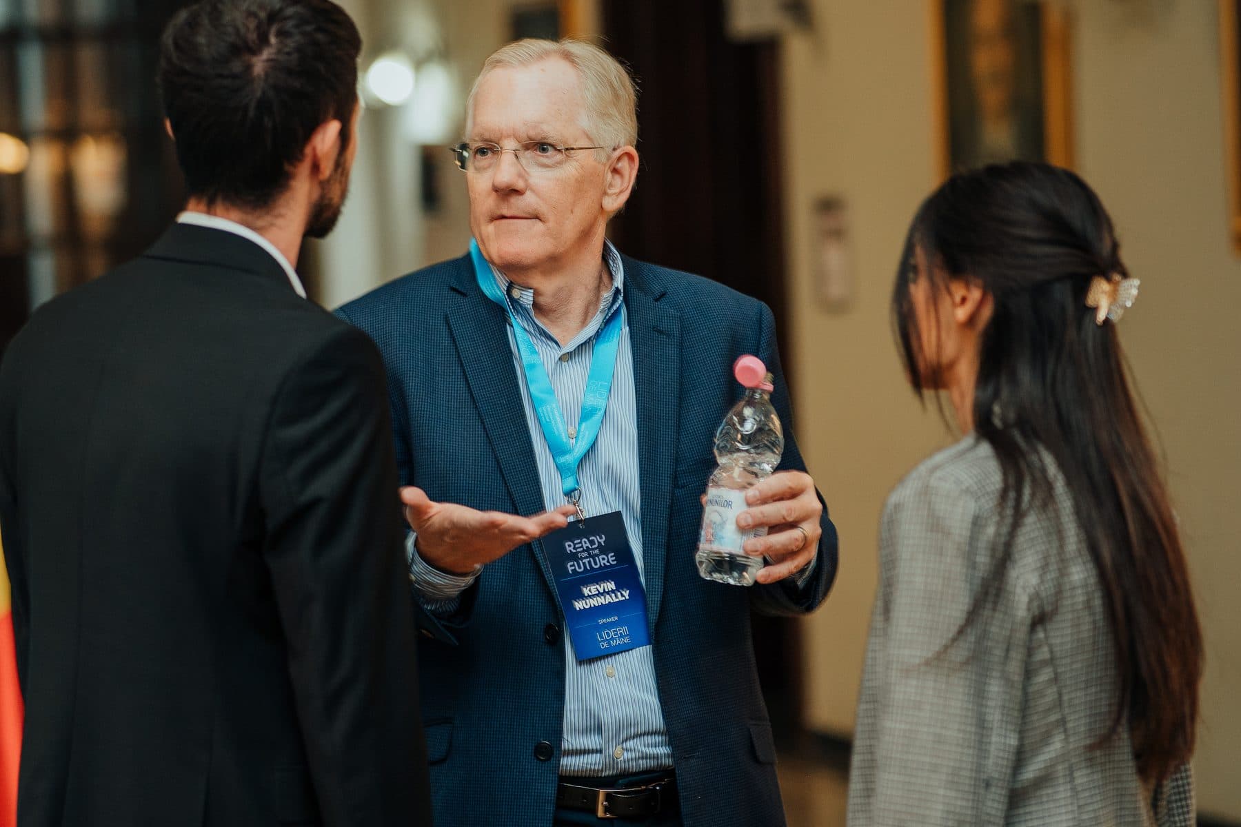 Mentor cu părul alb explică ceva unor studenți în pauza conferinței Ready for the Future