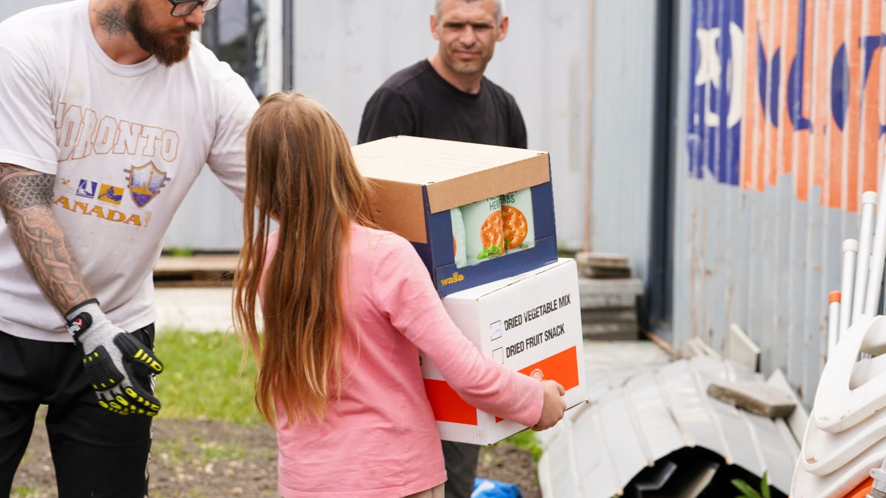 Fetiță în roz duce o cutie cu alimente primită de la voluntari, în proiectul de ajutor umanitar pentru Ucraina