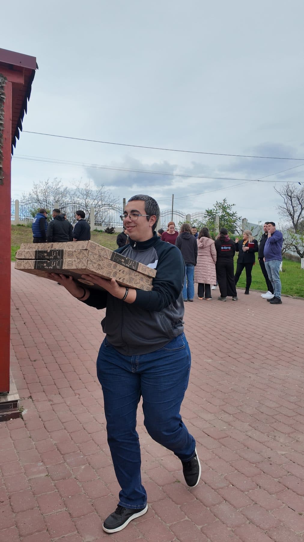 Bărbat care cară cutii de pizza pe o alee de cărămidă, la ieșirea LDM din județul Vaslui
